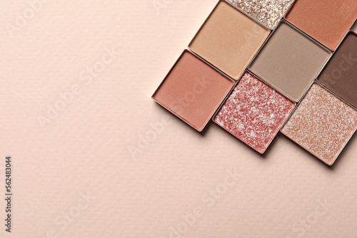 Different beautiful eye shadows on beige background, flat lay. Space for text