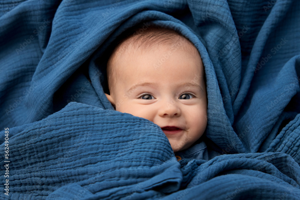 Portrait of smiling newborn baby wrapped in blue blanket Portrait of smiling newborn baby wrapped in blue blanket