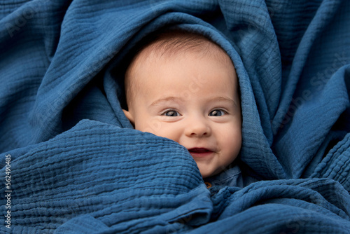 Portrait of smiling newborn baby wrapped in blue blanket