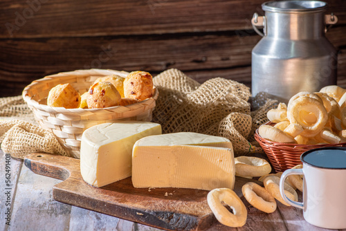 Cheese bread and more, cheese bread, manioc flour cookies and Minas cheese arranged on a rustic wooden surface with accessories, selective focus. photo