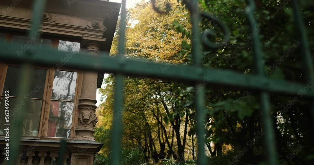 Old stone building guarded by green iron fence with autumn trees. High quality 4k footage Old stone building guarded by green iron fence with autumn trees. High quality 4k footage