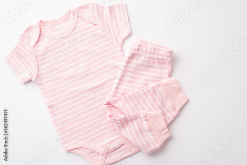Baby concept. Top view photo of pink infant clothes bodysuit and pants on isolated white background