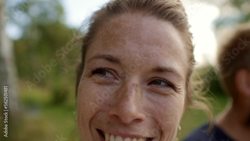 Woman laughing while enjoying an outdoor lunch with family and friends in summer