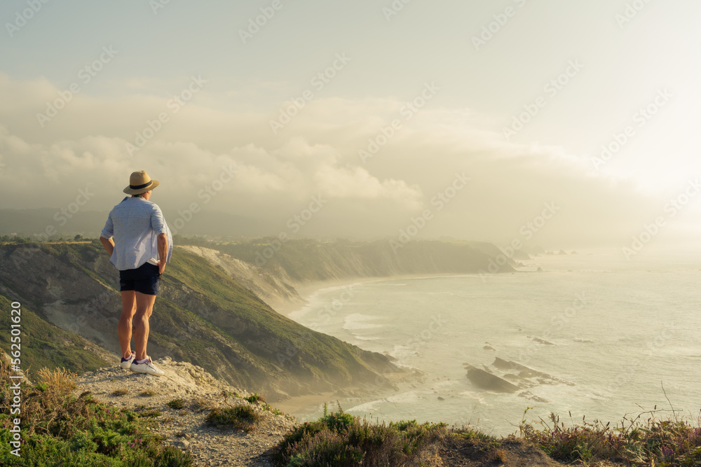 Tourist observing the cliff landscape at sunset. Travel concept.