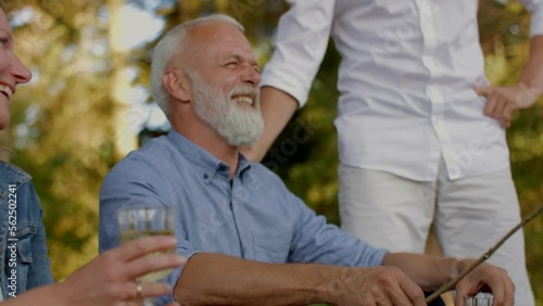 Mature man laughing outside during a summer afternoon campfire with family and friends