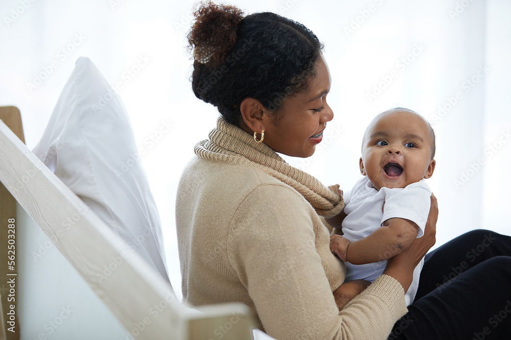 African young mother hugging and playing with her adorable baby on bed African young mother hugging and playing with her adorable baby on bed