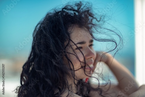 Sea woman rest. Portrait of a woman with long curly black hair in a beige dress stands on a balcony against the backdrop of the sea. Tourist trip to the sea.
