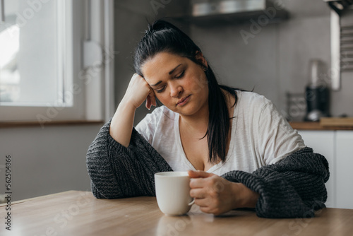 Tired woman sits in the kitchen at home