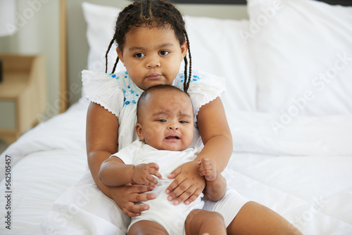 Quadro em tela African newborn baby crying and her sister soothing to stop crying on bed