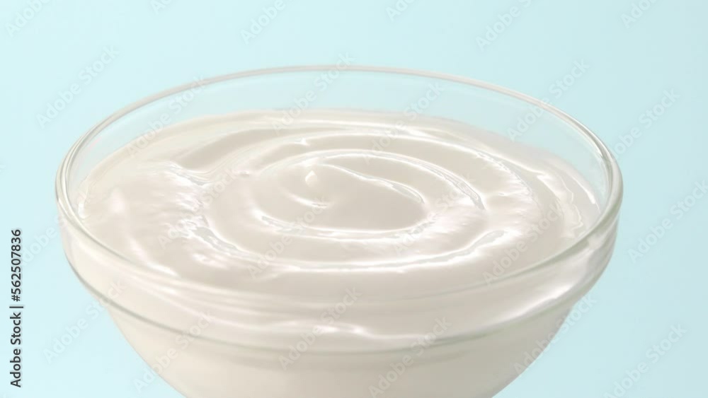 sour cream in a bowl. yogurt on a blue background. fermented milk products close-up. sour cream in a bowl. yogurt on a blue background. fermented milk products close-up.