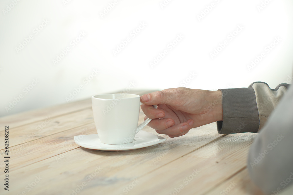 a person holding a cup with coffee in his hand on a table made of boards a person holding a cup with coffee in his hand on a table made of boards