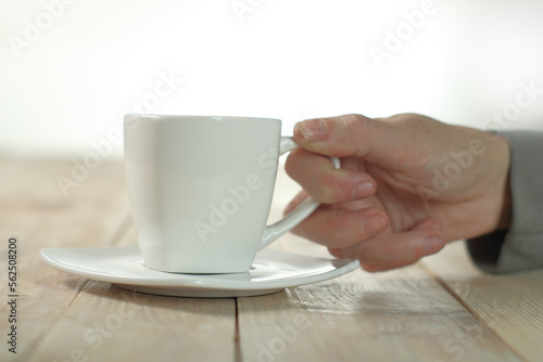 person holding a cup with coffee on a plank table