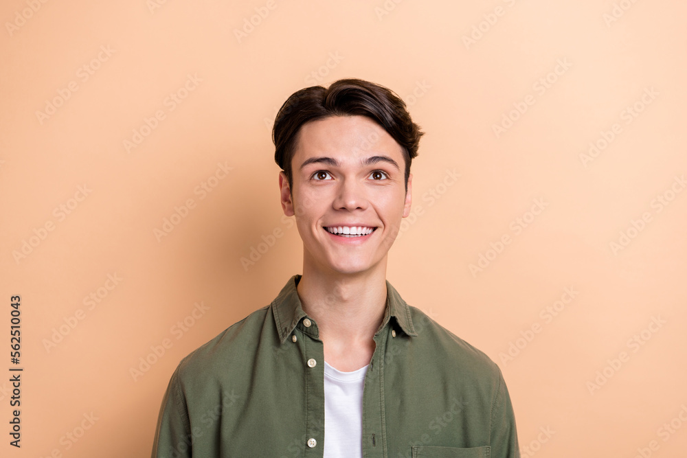 Portrait of nice cheerful man beaming smile look up empty space information isolated on beige color background Portrait of nice cheerful man beaming smile look up empty space information isolated on beige color background