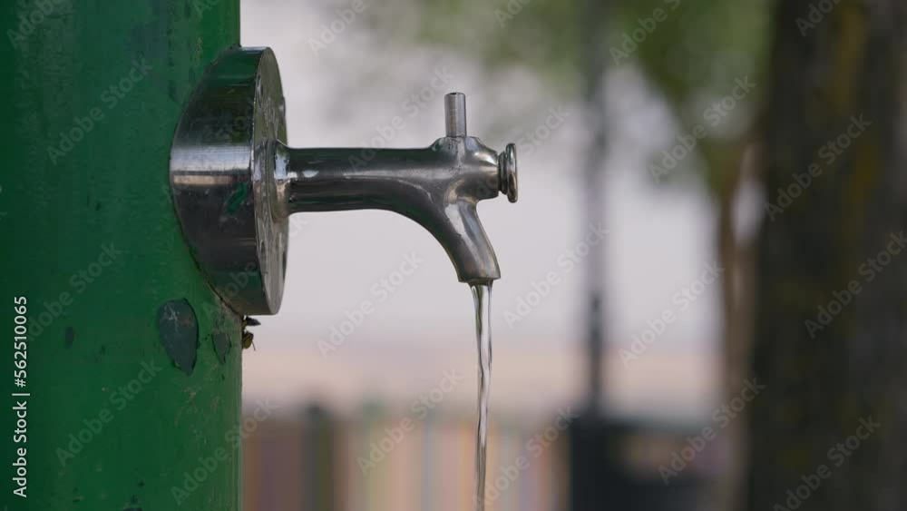 Fresh cold water running out outdoor faucet with bees flying around. Close-up refreshing liquid on street with insects in city Fresh cold water running out outdoor faucet with bees flying around. Close-up refreshing liquid on street with insects in city