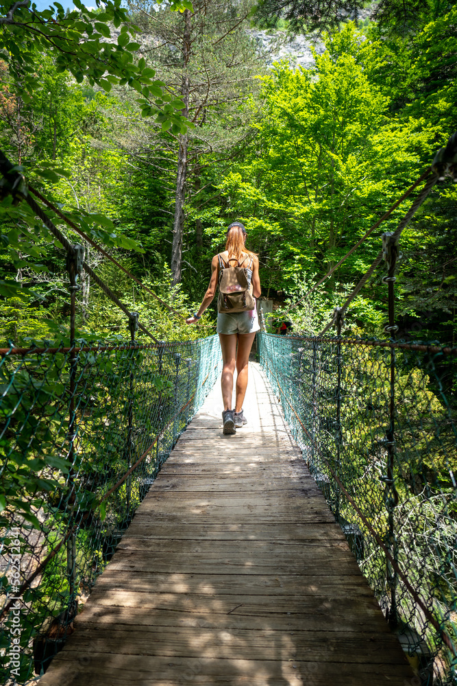 Young girl crossing a suspension bridge in the middle of a forest