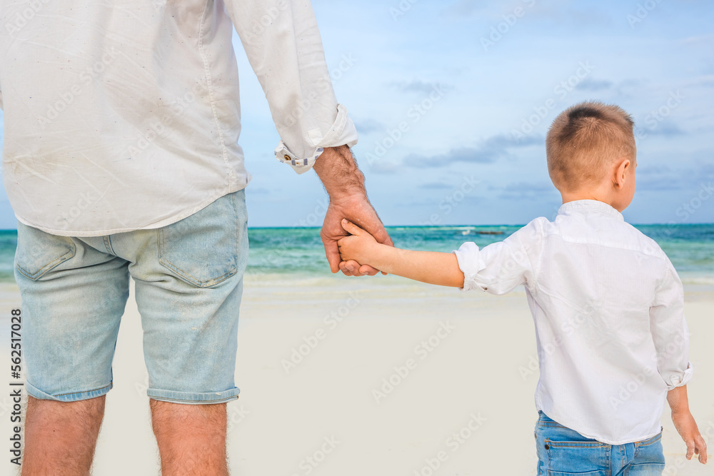 Fototapeta premium Father holding son's hand at the beach