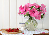 summer bouquet of pink and white lavatera in a glass vase and red currants on the table.