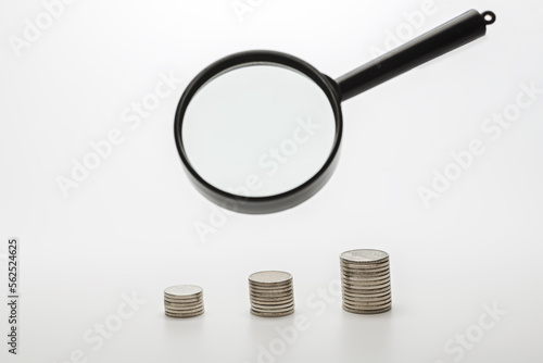 Magnifying glass with coins on gray background. Concept of banking, credit or search money.
