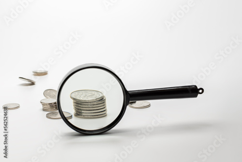 Magnifying glass with coins on gray background. Concept of banking, credit or search money.