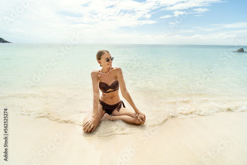 Beautiful woman in brown fashionable bikini enjoying sunny weather at the tropical beach. Freedom and carefree concept. © neonshot