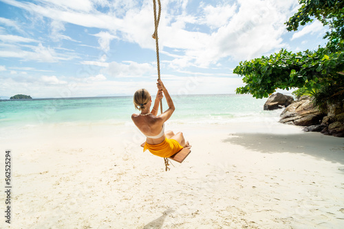 Happy woman on the tropical beach having fun on swing, sea shore during summer vacations. Copy space. Traveler. Tourist. Wanderlust. photo