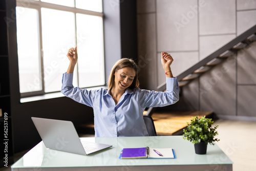 Happy excited woman at home workstation triumphing with raised hands