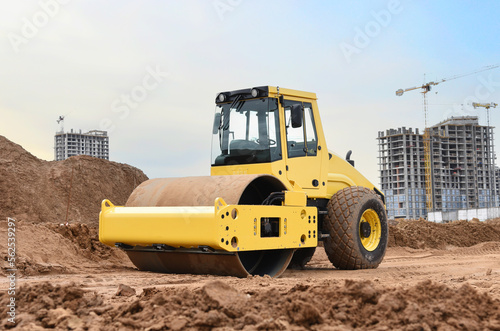 Soil Compactor for leveling ground for foundation and on road construction. Road compaction equipment at construction site. Vibration single-cylinder road roller on sunset. Building construction.