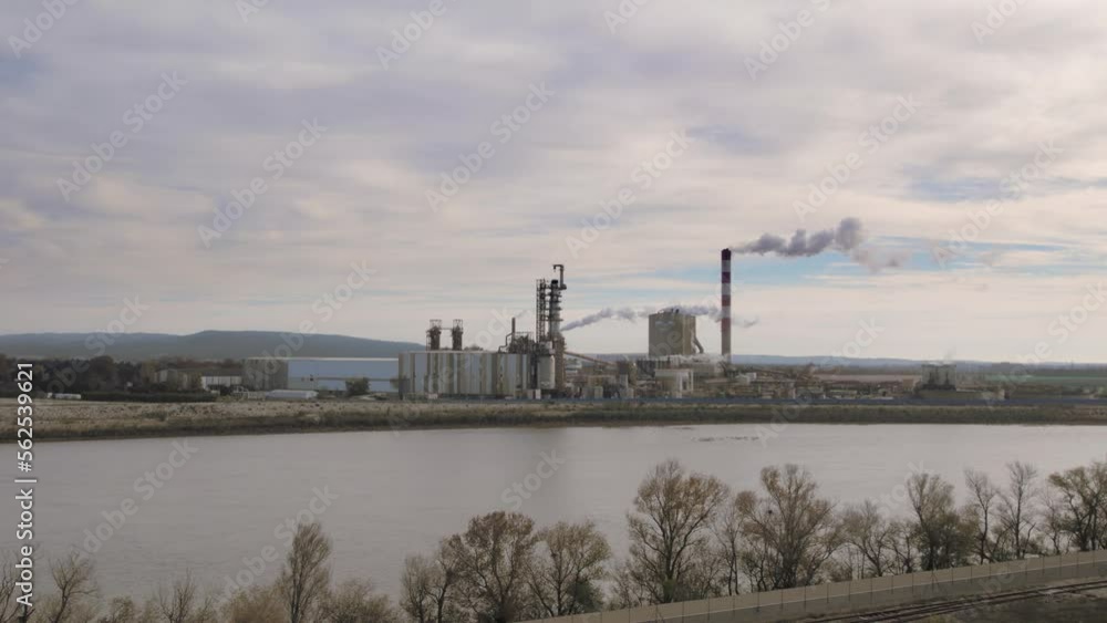 drone flies in reverse away from an Industrial Pile Smokes. Industrial Manufacturing Plant Next to a River drone flies in reverse away from an Industrial Pile Smokes. Industrial Manufacturing Plant Next to a River