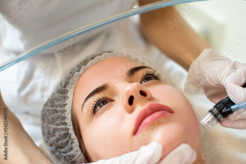 Closeup headshot of young woman receiving hydrafacial therapy at beauty salon