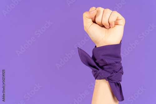 Closeup of closed fist and kerchief tied on wrist isolated on purple background. Feminism and protest concept with copy space photo