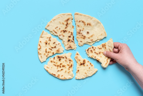 Indian flat bread above view. Woman taking a piece of naan bread photo