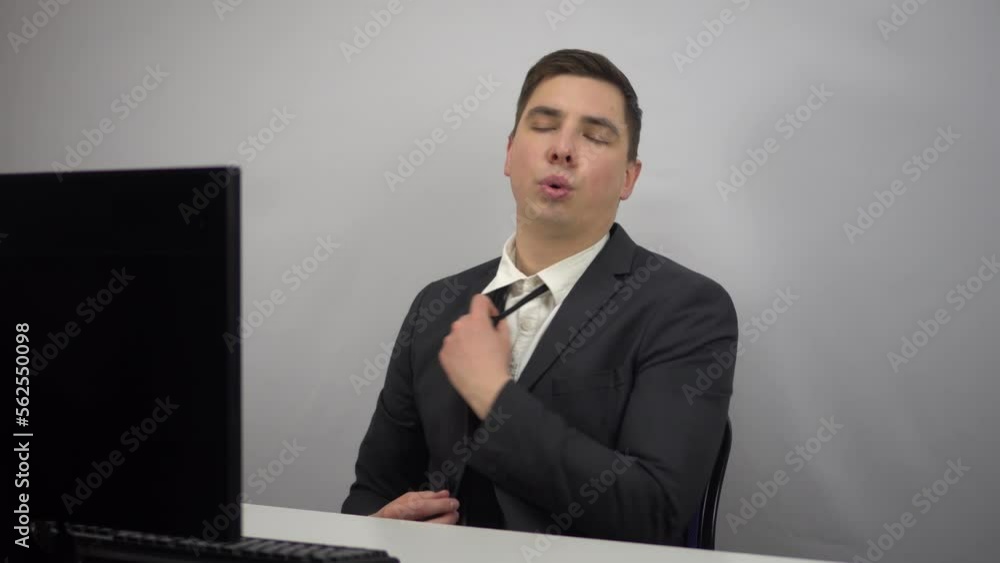 A young businessman is working hard and is now relaxed. A man in a suit has loosened his gauntlet and is resting while sitting in the office at the PC. A young businessman is working hard and is now relaxed. A man in a suit has loosened his gauntlet and is resting while sitting in the office at the PC.