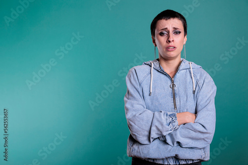 Фотография Portrait of sad unhappy woman standing with arm crossed while crying in studio with isolated background, person having negative emotion