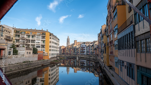 Colorful houses reflected in the Onyar river, in Girona, Catalonia, Spain. Church of Sant Feliu and Cathedral of Santa María in the background © martinscphoto