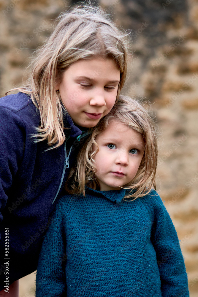 soeurs blondes jolies, 4 et 10 ans, portrait sur fond de mur de pierre soeurs blondes jolies, 4 et 10 ans, portrait sur fond de mur de pierre
