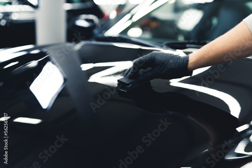 Car varnish protection. Ceramic coating application photographed on a black car. Car detailing process. Unrecognizable expert. High quality photo © PoppyPix