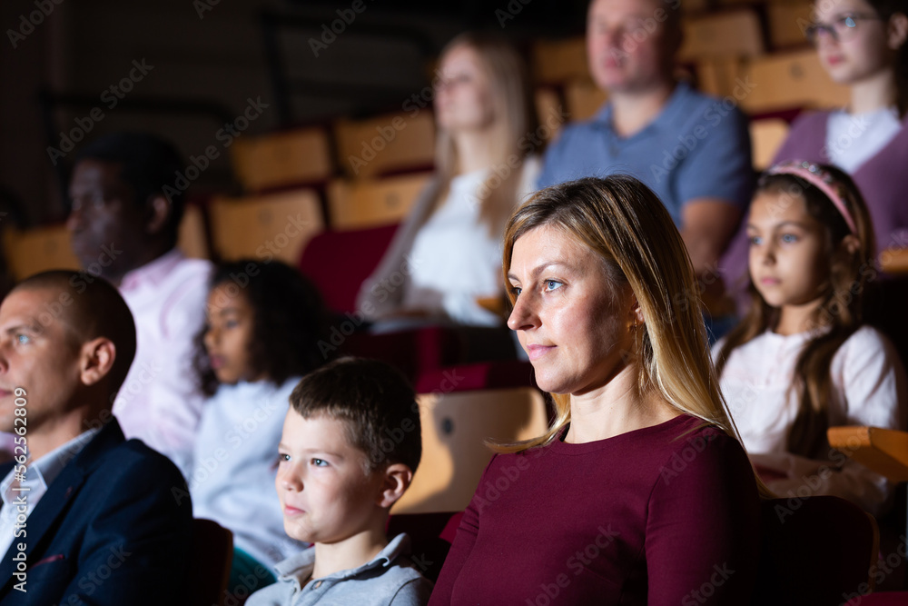 Portrait of interested woman theatergoer absorbedly watching stage performance in theater - obrazy, fototapety, plakaty 