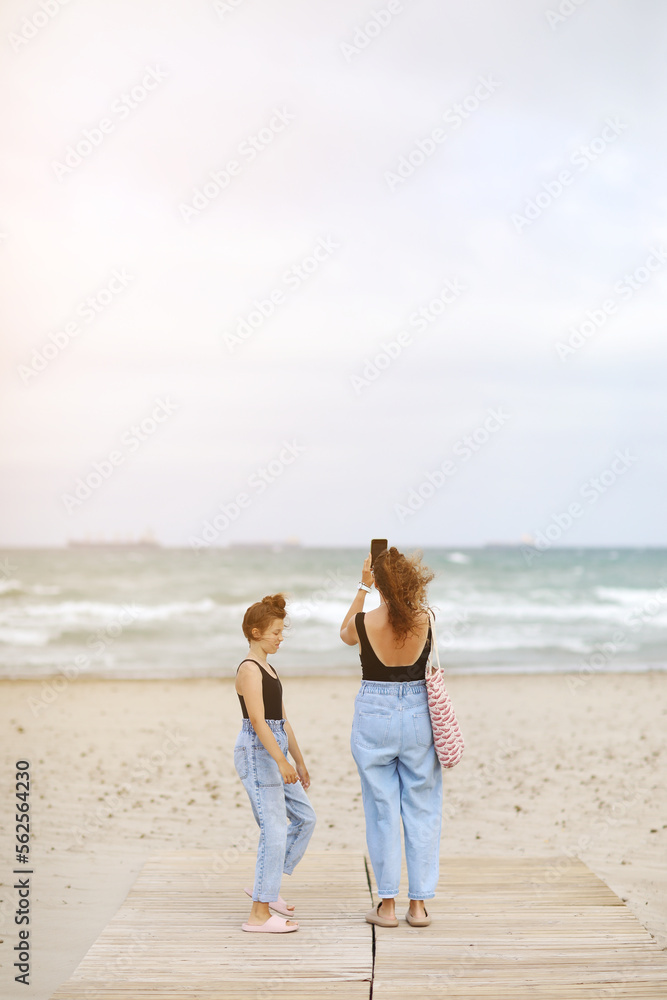 Happy family on beach vacation. Back view of mother and little daughter are walking together and holding hands on beach. Mom and child girl kid enjoy and having fun at summer holidays Happy family on beach vacation. Back view of mother and little daughter are walking together and holding hands on beach. Mom and child girl kid enjoy and having fun at summer holidays