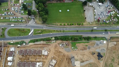 A look at the road, surrounded by a rural fair, where farm products are sold.
Cars drive in and out of town.
