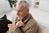 depressed man with parkinsonian syndrome and tremor in hands looking away while sitting at home.