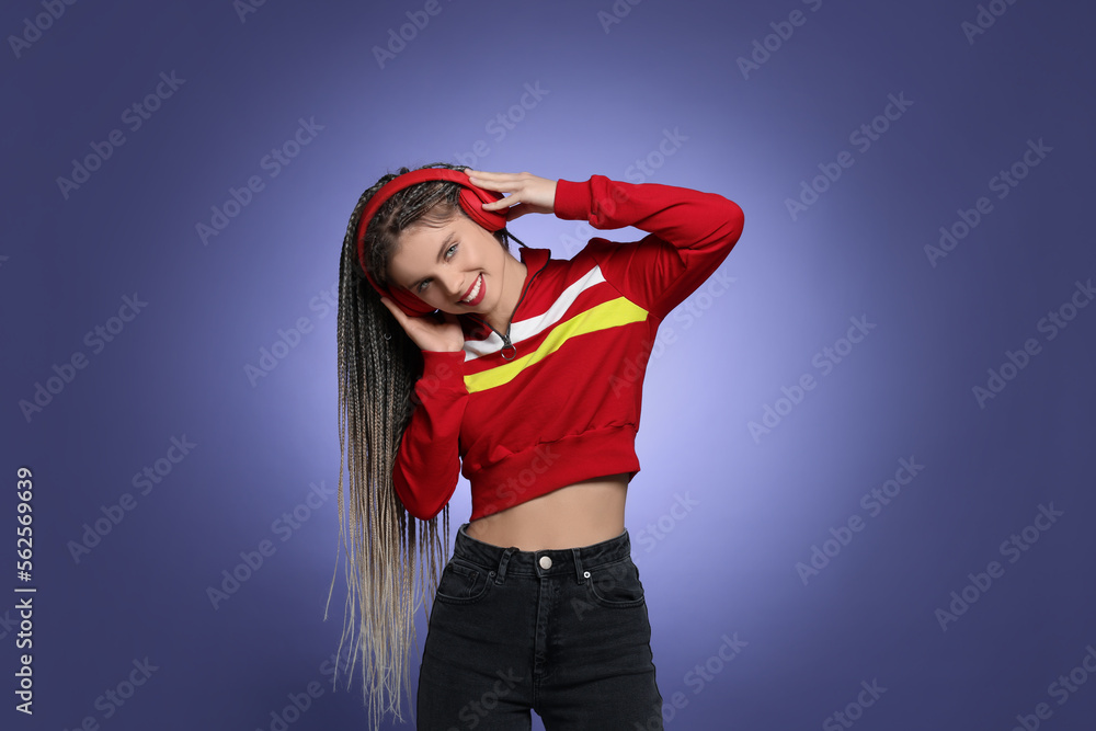 Beautiful woman with long african braids and headphones on purple background Beautiful woman with long african braids and headphones on purple background