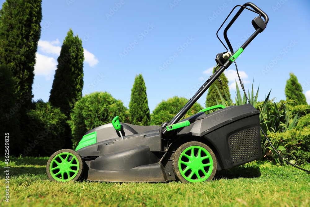 Fototapeta premium Lawn mower on green grass in garden