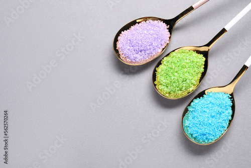 Spoons with colorful sea salt on light grey table, flat lay. Space for text