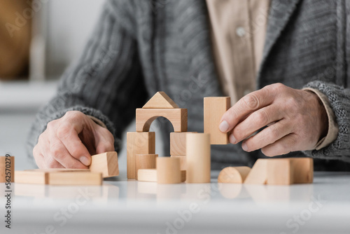 partial view of man with alzheimer syndrome playing therapy game with wooden blocks at home.