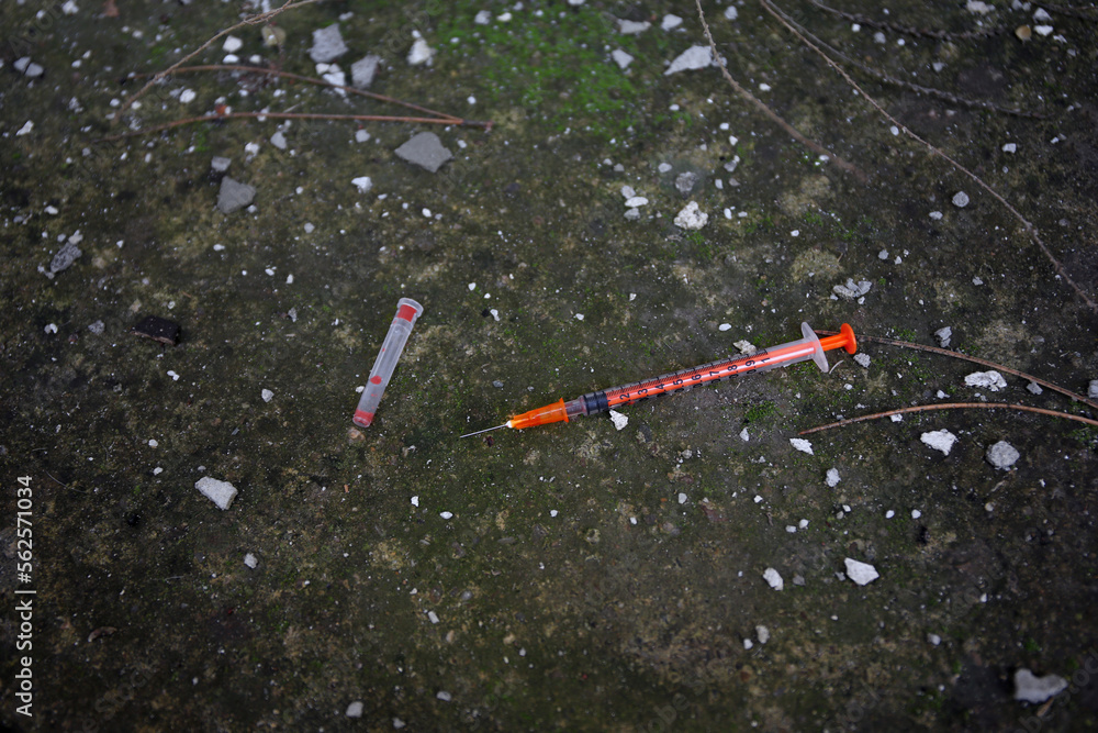 Naklejka premium Empty disposable syringe with needle on street