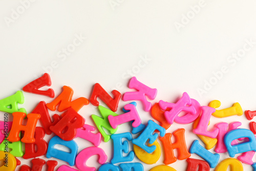 Many colorful magnetic letters on white background, flat lay. Space for text