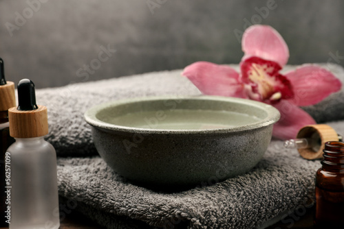 Bowl of essential oil and beautiful flower on wooden table. Aromatherapy treatment