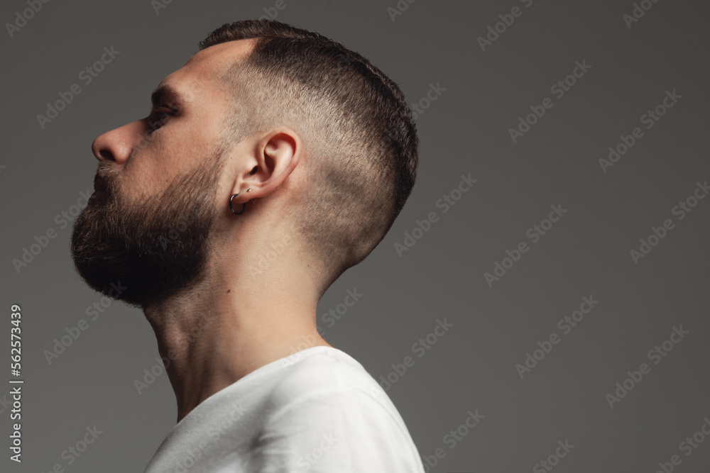 Male beauty concept. Profile portrait of proud charismatic active 30-year-old man posing over dark gray background. Perfect haircut. Hipster style. Close up. Copy-space. Studio shot Male beauty concept. Profile portrait of proud charismatic active 30-year-old man posing over dark gray background. Perfect haircut. Hipster style. Close up. Copy-space. Studio shot
