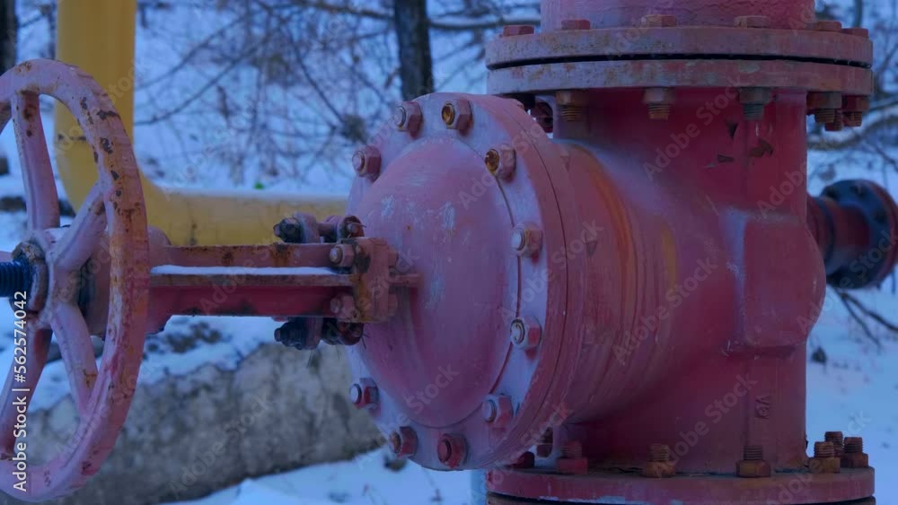 Natural gas main pipes of yellow color and a large red fuel regulating valve, in an open area in the frost in winter. Shot in motion Natural gas main pipes of yellow color and a large red fuel regulating valve, in an open area in the frost in winter. Shot in motion