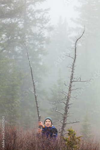 A man stands besides two dead trees in fog in McCurdy Park, Lost Creek Wilderness, Colorado. photo